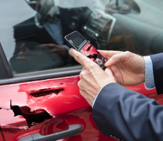 Homem a tirar fotografia ao seu carro partido