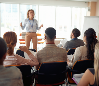 Professora a dar aulas numa sala com alunos mais velhos 