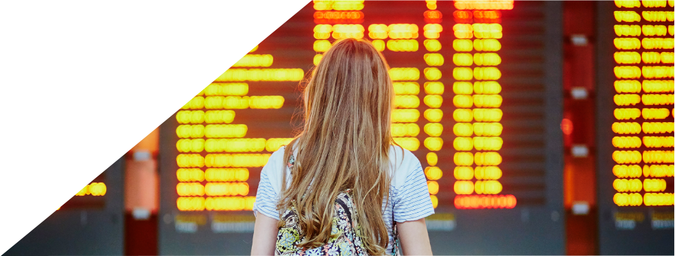 Mulher com mala de viagem na mão a ver um horário de transportes