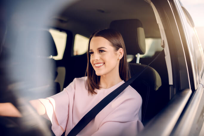 Mulher sorridente a conduzir o carro.