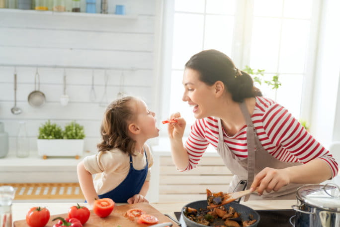 mãe dá comida à filha na cozinha