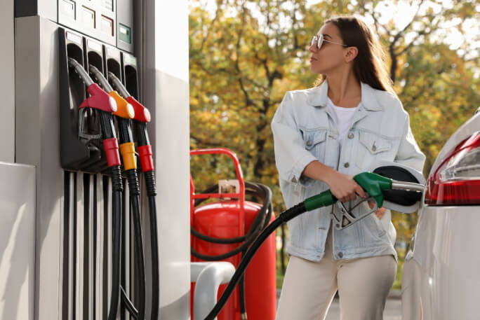 Mulher numa bomba de gasolina a abastecer o carro de combustível