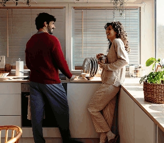 Casal a conversar alegremente numa cozinha moderna.