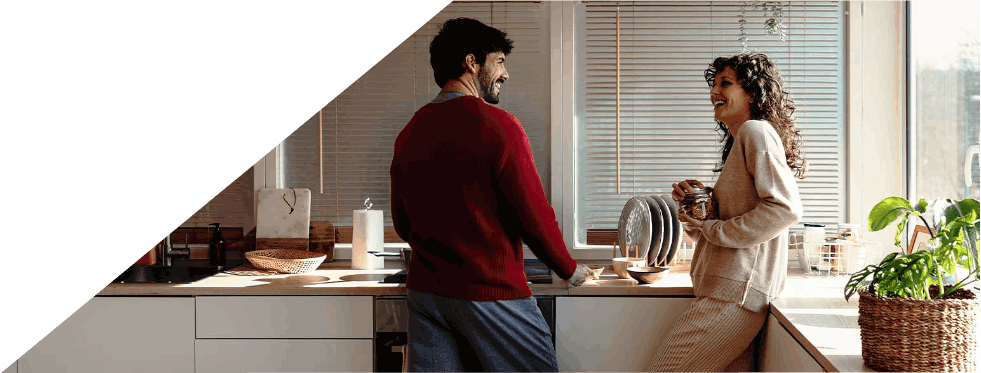 Casal a conversar alegremente numa cozinha moderna.