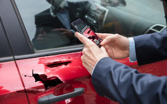 Homem a fotografar com o telemóvel danos no carro