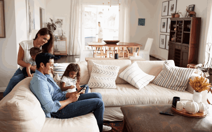 Família feliz, no sofá da sala, a gerir a sua estratégia de investimento em conjunto.