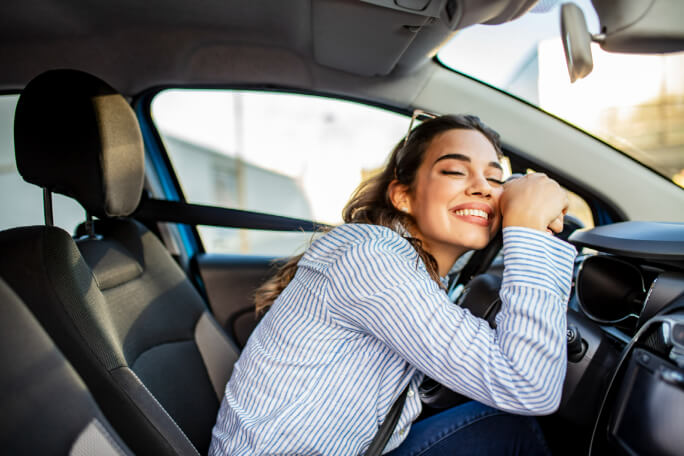Jovem mulher feliz por comprar um carro.