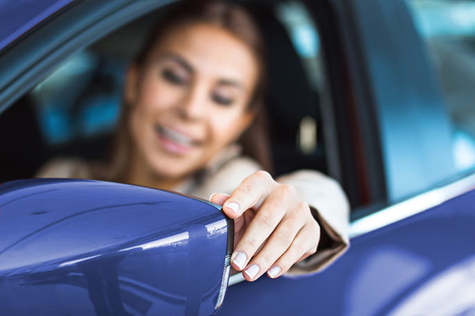 mulher a ajustar o espelho do carro