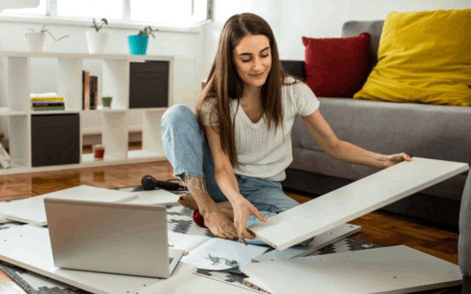Mulher jovem faz as suas próprias reparações em casa, montando umas prateleiras.