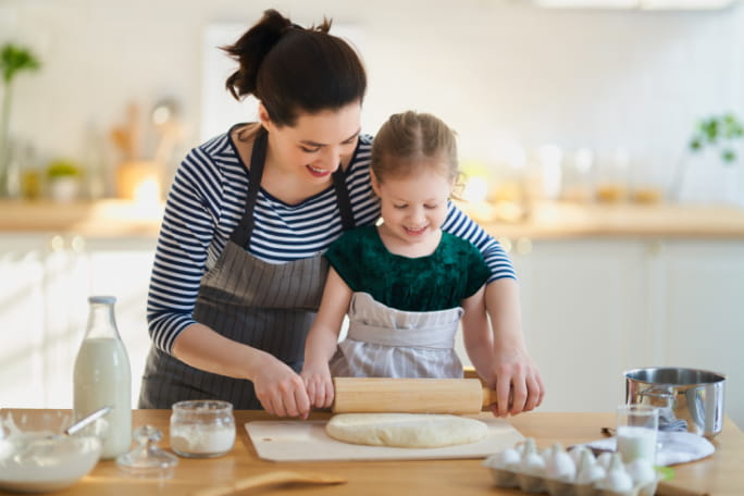 Mãe e filha a esticar massa na cozinha.