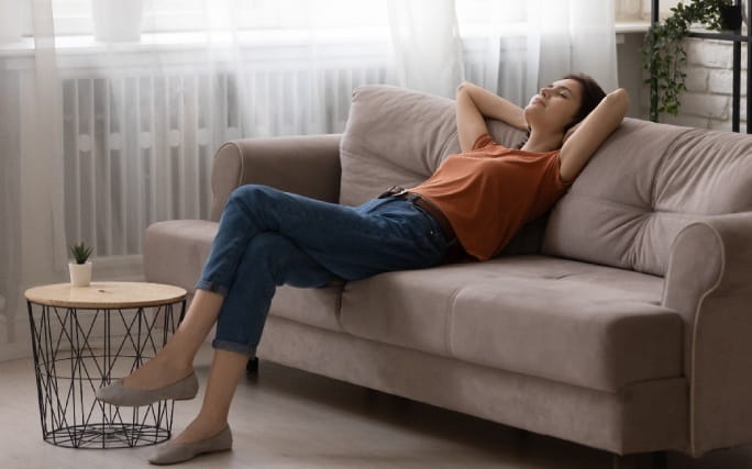 Jovem mulher a relaxar no sofá depois de aprender a relativizar.