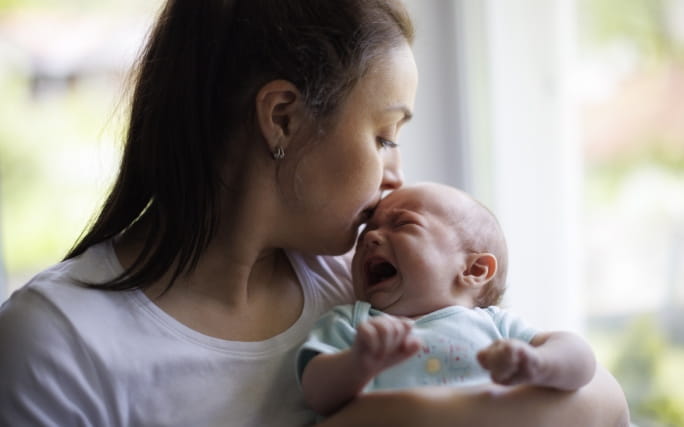 Mãe pega num bebé pequeno que chora convulsivamente.