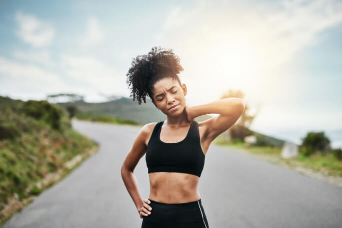 Jovem numa pista de atletismo com dor muscular