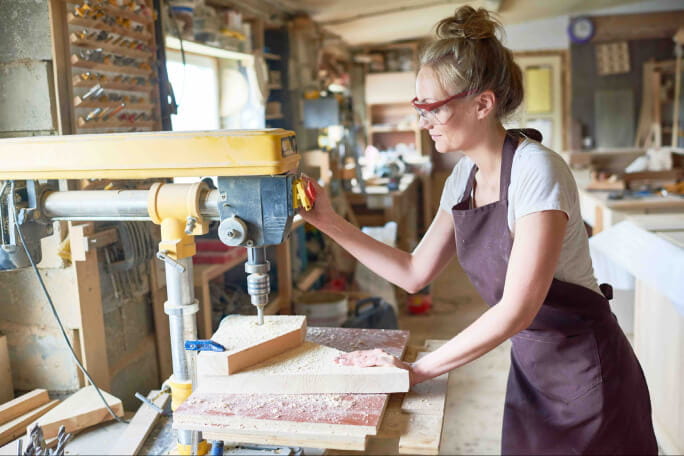 Mulher a trabalhar com uma máquina que pode gerar acidentes de trabalho