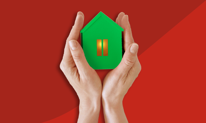 Imagem com fundo vermelho com mãos a segurar uma casa de cor verde.