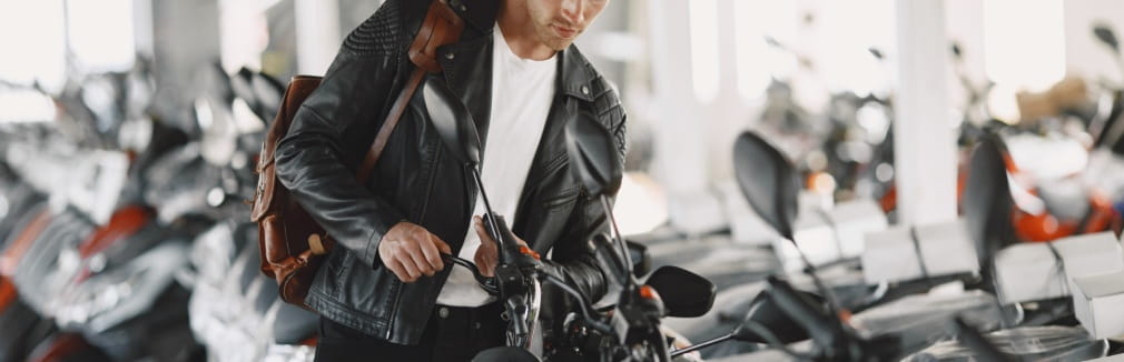 Jovem num stand de vendas à procura da moto ideal para pequenas viagens.