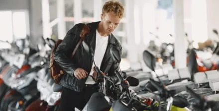 Jovem num stand de vendas à procura da moto ideal para pequenas viagens.