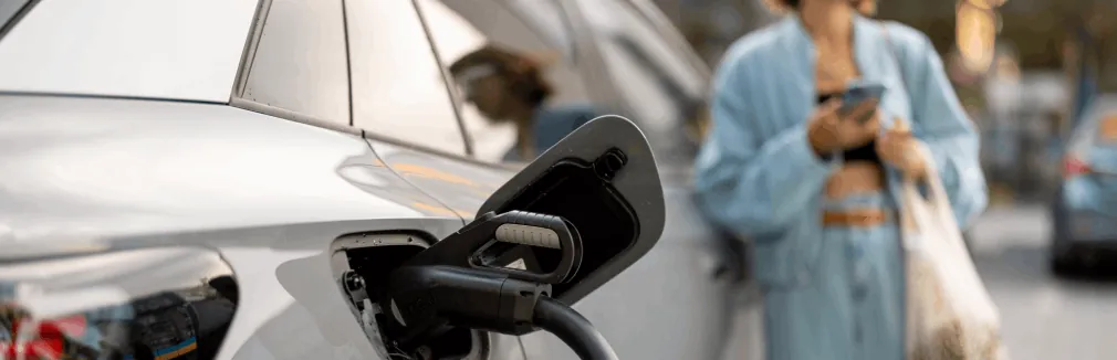 Rapariga aguarda num ponto de abastecimento por carregamento carro elétrico.